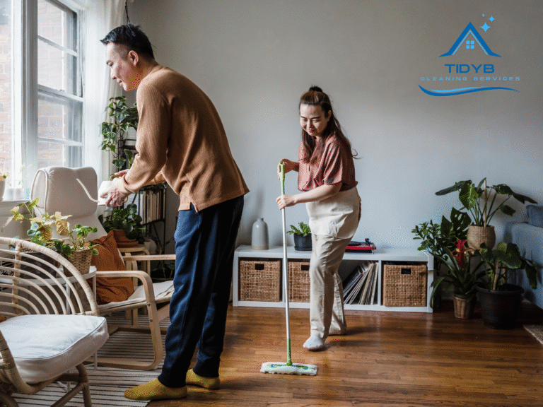 Couple cleaning a bright living room while watering green houseplants